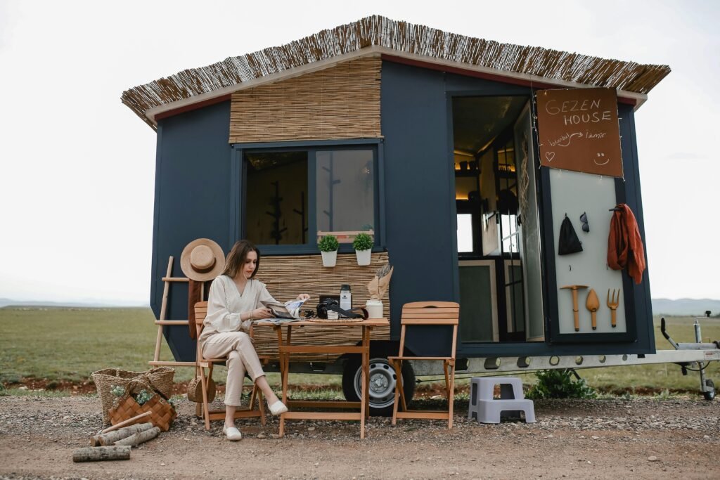 Woman sitting outside a boho-style mobile home, enjoying tranquility.