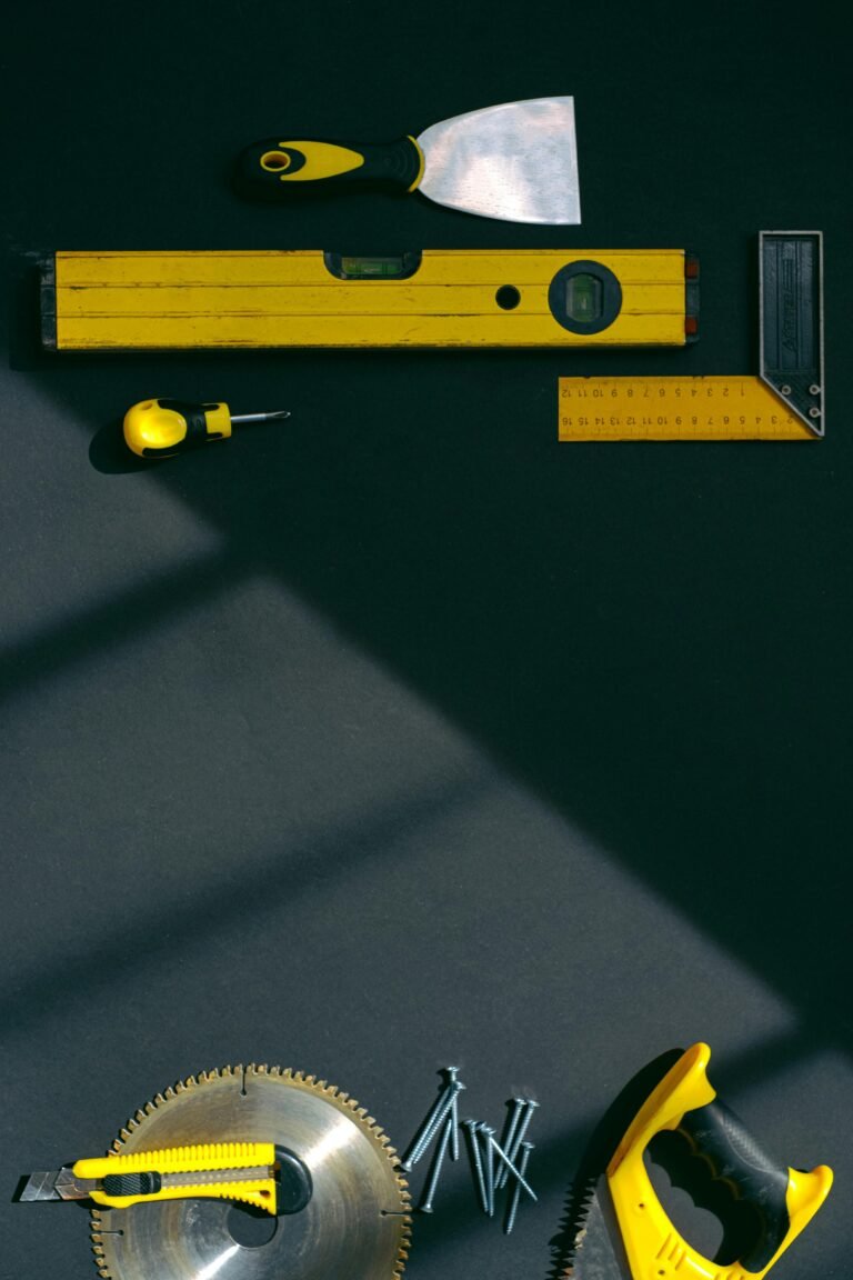 Stylized flat lay of yellow hand tools on a dark surface with dramatic lighting.