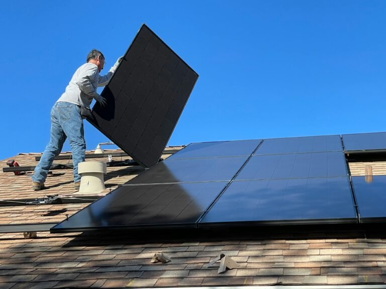 A worker installs solar panels on a sunny day, highlighting renewable energy solutions.